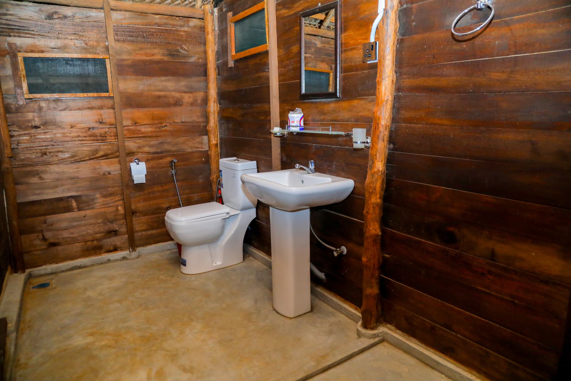 Modern bathroom interior with rustic wooden walls, a white washbasin, and contemporary fixtures — comfort in the wild.