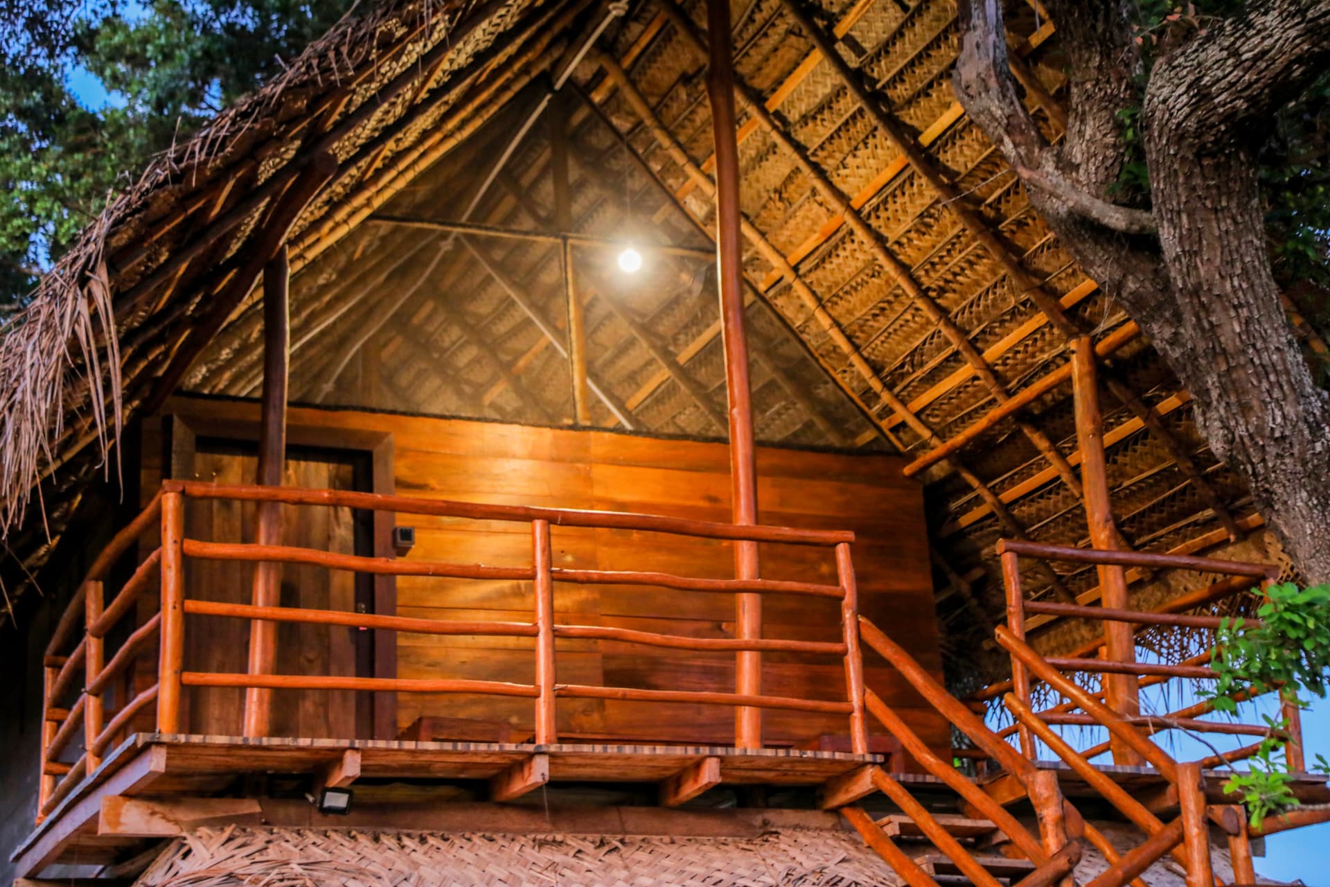 The upper balcony deck at dusk, glowing with warm ambient lighting — a perfect spot to unwind after a Yala wildlife safari.