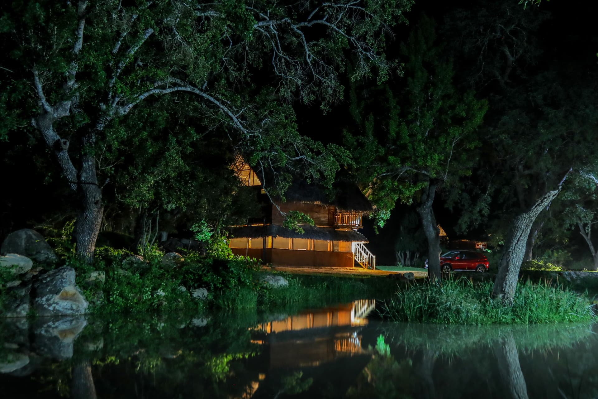 A magical night view of the illuminated Nature Win Yala cabana reflecting in the still water of the nearby pond.